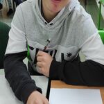 Uczeń siedzi przy stole. Przed nim leży odwrócona kartka z testem.