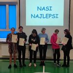 Nagrodzeni uczniowie z mamami. Obok stoi pani vicedyrektor, Po bokach siedzą uczniowie.