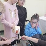 Uczennice przyglądają się koleżance lejącej wosk przez klucz..