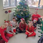 Grupa uczniów siedzi pod choinką.
