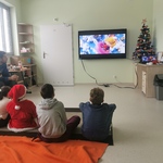 Uczniowie siedzą na podłodze i oglądają film.