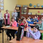 Uczestnicy konkursu siedzą przy stolikach. Z tyłu stoją nauczyciele.