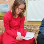 Uczennica siedzi na podłodze i czyta list od Mikołaja.