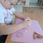 Uczennica siedzi przy stoliku i dekoruje piernik.