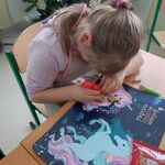 Uczennica siedzi przy stoliku i dekoruje piernik.