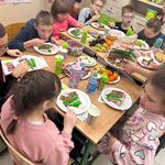 Uczniowie siedzą przy stole i jedzą tort
