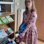 Uczennica wkłada torbę z karmą dla zwierząt do kartonowego pudełka.