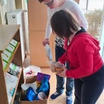 Uczennice wkładają do kartonu rzeczy dla zwierząt przyniesione przez uczniów.