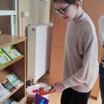 Uczennica wkłada do kartonu rzeczy dla zwierząt przyniesione przez uczniów.
