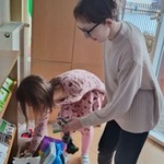 Uczennice wkładają do kartonu rzeczy dla zwierząt przyniesione przez uczniów.