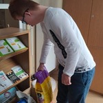 Uczeń wkłada do kartonu rzeczy dla zwierząt przyniesione przez uczniów.