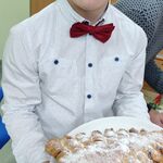 Uczeń trzyma talerz z ciastem w kształcie choinki.