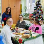Wychowawczyni stoi u szczytu stołu. Wokół stołu wigilijnego siedzą uczniowie.