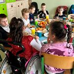 Uczniowie siedzą przy stole jedząc wigilijne potrawy.