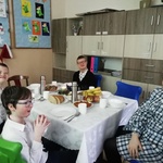 Grupa uczniów siedzi przy wigilijnym stole.