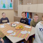 Grupa uczniów siedzi przy urodzinowym stole.