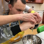 Uczeń z pomocą nauczycielki wbija jajko do miski.