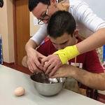 Uczeń z pomocą nauczycielki wbija jajko do miski.