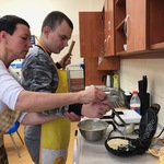 Uczeń z pomocą nauczycielki nalewa ciasto do gofrownicy