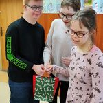 Dwie uczennice składają życzenia, wręczają solenizantowi prezent.