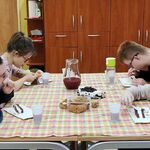 Uczniowie siedzą przy stole i jedzą tort i przekąski