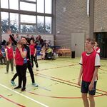 Zawodnicy na boisku podczas meczu ringo. Z tyłu na siedzeniach siedzą uczniowie obserwujący mecz.