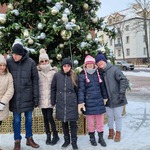 Grupa uczniów stoi przed choinką.
