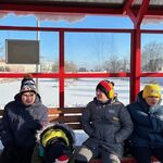 Uczniowie siedzą na przystanku autobusowym.