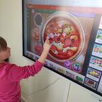 Uczennica układa puzzle - pizzę na tablicy interaktywnej.