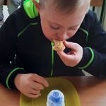 Uczeń siedzi przy stoliku i je pizzę.