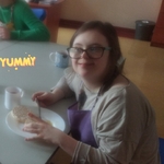 Uczennica siedzi przy stole i je przygotowany posiłek.