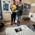 Nauczycielka podaje uczniowi żółtą łapkę na muchy.
