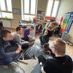 Uczniowie siedzą na dywanie i obserwują nauczycielką w przebraniu.
