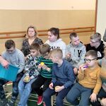 Uczniowie losują kolorowe piłki z pojemnika trzymanego przez nauczyciela.
