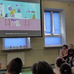 Uczniowie siedzą na ławkach i oglądają wyświetlany na ekranie film.