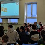 Uczniowie siedzą na ławeczkach i oglądają wyświetlany film.