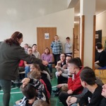 Pani prowadząca zadaje pytanie uczniom siedzącym na ławkach.