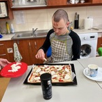 Uczeń kładzie kawałki sera na pizzę.