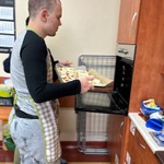 Uczeń z pomocą nauczyciela wstawia blachę z pizzą do piekarnika.