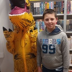 Uczeń stoi obok osoby przebranej w strój dinozaura.