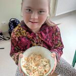 Uczennica trzyma miskę z wykonaną przez siebie sałatką.
