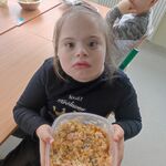 Uczennica trzyma miskę z wykonaną przez siebie sałatką.
