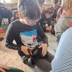 Uczeń siedzi na dywanie i głaszcze królika,