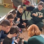 Uczniowie siedzą na dywanie, patrzą na szynszyla.