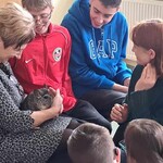 Nauczycielka trzyma szynszyla na kolanach, uczniowie przyglądają się.
