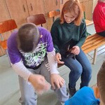 Uczeń i pani prowadząca siedzą na krzesłach. Na kolanach Pani ma królika