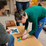 Uczeń układa na stoliku motyla z drewnianych puzzli.