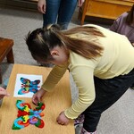 Uczennica układa motyla z kolorowych puzzli.