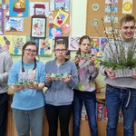 Grupa uczniów trzyma w rękach kolorowe jajka i stroik z gałązek.