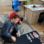 Nauczycielka i uczniowie siedzą na dywanie i układają zdjęcia.